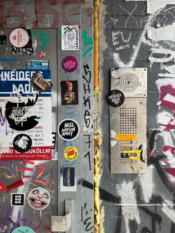 A door and accompanying buzzer, covered in graffiti and stickers At least one of them reads 'Synthesizer Museum Berlin.'