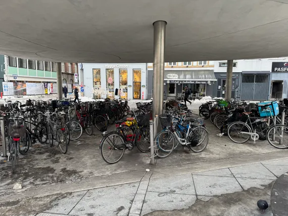 Maybe 100 bikes parked tightly on a plaza, with snow in the background.