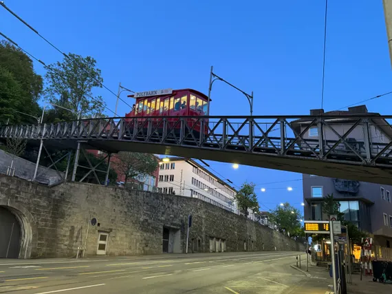 A funicular tram crossing over a city road at twilight.